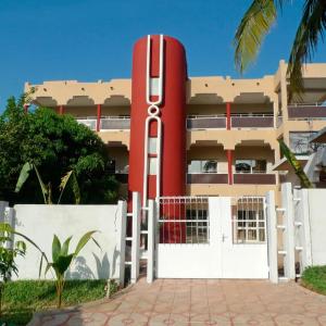 a building with a large red object behind a white fence at OABY'S Hôtel in Bobo-Dioulasso