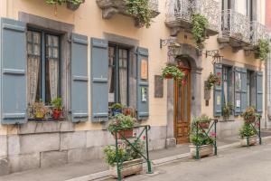 un bâtiment avec des plantes en pot sur son côté dans l'établissement Hôtel du Lion d'Or, à Cauterets