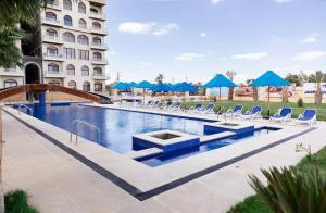a swimming pool with blue chairs and a building at Lurret Hotel in Qaryat at Ta‘mīr as Siyāḩīyah