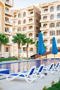 a group of chairs and umbrellas next to a swimming pool at Lurret Hotel in Qaryat at Ta‘mīr as Siyāḩīyah