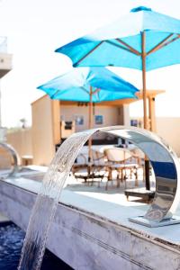 a pool with water coming out of a fountain with umbrellas at Lurret Hotel in Qaryat at Ta‘mīr as Siyāḩīyah +2 photos