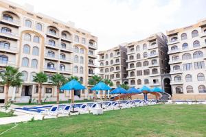 a group of buildings with chairs and blue umbrellas at Lurret Hotel in Qaryat at Ta‘mīr as Siyāḩīyah