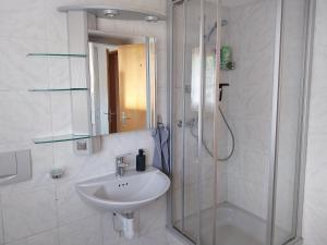 a bathroom with a sink and a shower with a mirror at 1 Zimmer Unterkunft in Spiez