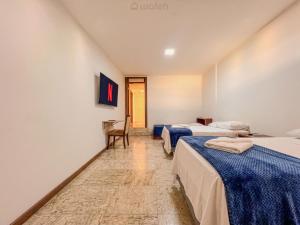 a hotel room with two beds and a chair at Wafeh Pampulha Suítes in Belo Horizonte