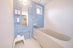 a bathroom with a white tub and blue tiles at がじゅまる Miyako Hotel in Miyakojima