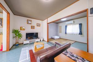 a living room with a couch and a tv at がじゅまる Miyako Hotel in Miyakojima