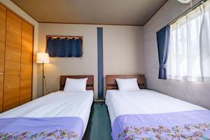 two beds sitting next to each other in a room at がじゅまる Miyako Hotel in Miyakojima