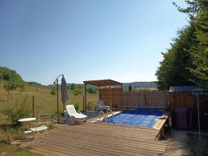 a deck with a pool and a table and chairs at maisonnette entre bois et champs in Crest