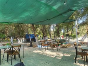 a group of tables and chairs under a green tent at Micro Africa Camping Site in Delvinë