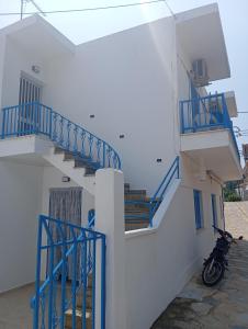 a motorcycle parked next to a white building with blue stairs at George Rooms in Votsi