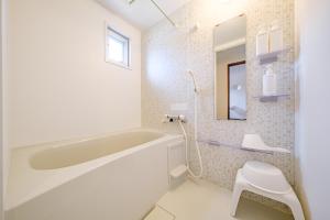 a white bathroom with a tub and a toilet at キジムナー MIYAKO Hotel in Miyakojima