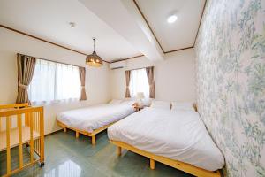 a bedroom with two beds and a crib at キジムナー MIYAKO Hotel in Miyakojima