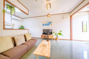 a living room with a couch and a tv at キジムナー MIYAKO Hotel in Miyakojima