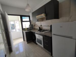 a kitchen with black cabinets and a white refrigerator at heartofrabat in Rabat