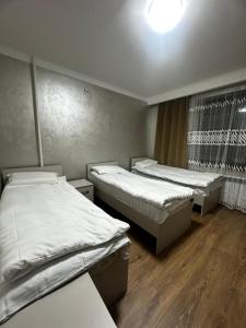 two twin beds in a room with wooden floors at Guest house 97 in Karakol +7 photos