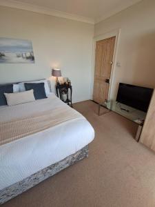 a bedroom with a bed and a flat screen tv at Glenlara House in Youghal