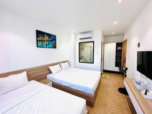 a hotel room with two beds and a flat screen tv at The Track Homestay - Near Bai Dai Beach in Cam Lâm