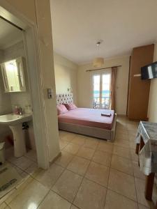 a bedroom with a bed and a sink and a window at Karyatis studios lixouri in Lixouri