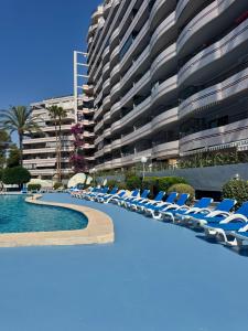 a swimming pool with lounge chairs and a large building at Calpe Paraiso Playa primera linea in Calpe