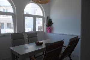 a dining room with a table and chairs and two windows at Busho Residence 2 in Naousa
