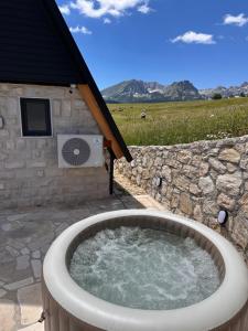 a hot tub in a yard with a stone wall at Durmitor Panorama in Žabljak
