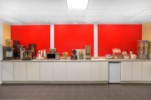 a kitchen with a red wall and a counter at Super 8 by Wyndham Dunn in Dunn