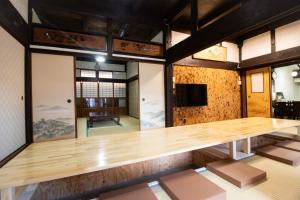 ein großer Holztisch in einem Zimmer mit Fenstern in der Unterkunft Kominka Wagaya in Higashiōsaka