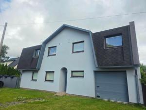 a white house with a black roof and a garage at Tähe Holiday Home in Pärnu