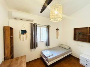 a room with a bed and a window and a chandelier at Al Yakhour Hostel in Haifa