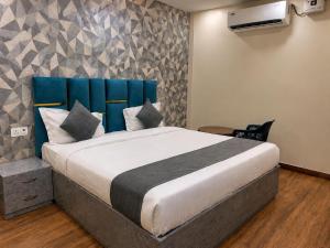 a bedroom with a large bed with a blue headboard at HOTEL RAAS PLAZa in Kānpur +9 photos