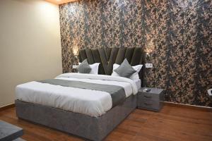 a bedroom with a king sized bed with a floral wallpaper at HOTEL RAAS PLAZa in Kānpur