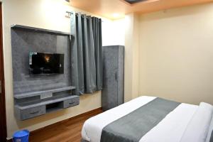 a bedroom with a bed and a tv on a wall at HOTEL RAAS PLAZa in Kānpur