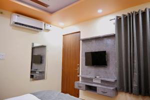 a bedroom with a bed and a tv on the wall at HOTEL RAAS PLAZa in Kānpur