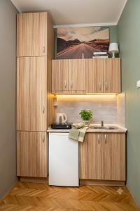 a kitchen with wooden cabinets and a white refrigerator at Apartment Wonderland in Niš