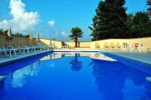 a swimming pool with chairs and blue water at La villa des palmiers in Soublecause
