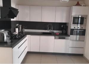 a white kitchen with white cabinets and a microwave at Maison de vacance Montpellier in Montpellier