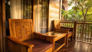 a porch with two chairs and a table on a balcony at Indraprastha 2 Bungalow in Ubud