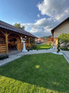 a large yard with a pavilion and a house at Pensiunea Edy in Statjunea Borsa