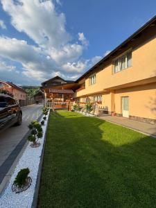a house with a lawn in front of a building at Pensiunea Edy in Statjunea Borsa
