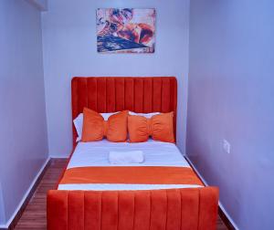 a red bed with orange pillows in a room at Kakamega bransoncomfort in Kakamega