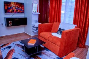 a living room with a red chair and a tv at Kakamega bransoncomfort in Kakamega