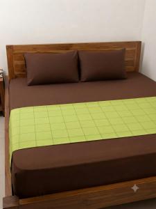 a bed with a wooden headboard and brown sheets at The White Grand Heritage in Balangoda