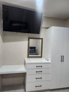 a room with a white dresser with a mirror and a tv at K&C RENTALs in Mount Gay