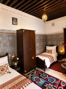 a bedroom with two beds and a rug at Riad Fes Layan in Fez