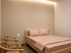 a small bedroom with a bed and a wooden chair at KAKA HOTEl - KDC TÂN ĐỨC in Ðức Hòa +5 photos