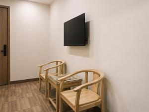 a room with two chairs and a table and a tv on a wall at KAKA HOTEl - KDC TÂN ĐỨC in Ðức Hòa