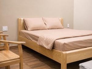 a bed with a wooden frame with a pillow on it at KAKA HOTEl - KDC TÂN ĐỨC in Ðức Hòa