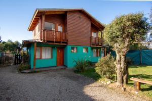 a house with a deck and a bench in front of it at Cabañas Lago Guillelmo in San Carlos de Bariloche