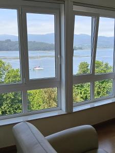 a window with a view of a boat in the water at Casa Vistas in Santa Marta de Ortigueira