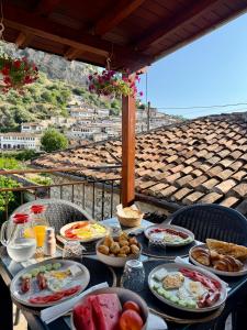 a table with plates of breakfast food on a balcony at MEROLI Guesthouse - UNESCO quarter in Berat